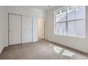 Bright bedroom features neutral carpet, a large window for natural light, and a sliding-door closet at 2128 S Haleyville Way, Aurora, CO 80018