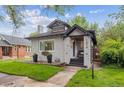 Charming house showing front yard, porch, and lush landscaping, complemented by blue skies and mature trees at 1870 S Ogden St, Denver, CO 80210