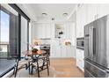 Bright kitchen with white cabinets, stainless steel appliances, and a cozy dining area with city views at 1750 Wewatta St # 1825, Denver, CO 80202