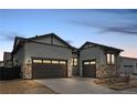 View of the home's gray exterior featuring a driveway with a 3-car garage at 11452 Autumn Moon St, Littleton, CO 80125