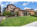 A stone-accented home with a manicured lawn and landscaping that enhances the curb appeal and natural beauty at 9487 Winding Hill Way, Lone Tree, CO 80124