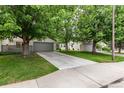 Exterior shot of home with lush green lawn, mature trees and gray two-car garage at 1633 S Trenton St, Denver, CO 80231