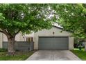 Inviting home exterior with a lush lawn, mature tree, and a gray two-car garage at 1633 S Trenton St, Denver, CO 80231