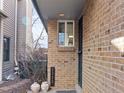 Inviting entryway with brick facade, unit number, decorative pots and a well-lit covered porch at 2323 S Jamaica St, Aurora, CO 80014