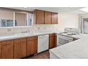 Well-lit kitchen featuring oak cabinets, marble-look countertops, white appliances, and a bright window view at 2323 S Jamaica St, Aurora, CO 80014