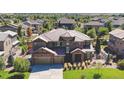 A luxurious home boasts a well-manicured lawn and a three-car garage, surrounded by mature trees at 1440 Eversole Dr, Broomfield, CO 80023