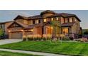 Beautiful home featuring a landscaped front yard with lush greenery, stone accents, and three-car garage at 1440 Eversole Dr, Broomfield, CO 80023