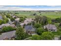 Aerial view of a neighborhood with green lawns, mature trees, and a home backing to a farm at 2240 Summitview Dr, Longmont, CO 80504