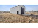 A detached garage with a dark door and white siding on a flat, grassy lot at 11200 E 166Th Ave, Brighton, CO 80602