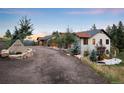 Exterior of the home shows stone address monument and a large circular driveway that leads to the main residence at 21798 Wagon Rim Trl, Morrison, CO 80465