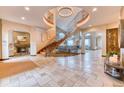 Grand foyer with travertine tile flooring and a sweeping staircase with wrought iron railings at 16713 W Archer Ave, Golden, CO 80401
