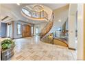 Elegant foyer with travertine tile, a sweeping staircase and large arched doorways at 16713 W Archer Ave, Golden, CO 80401