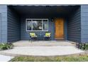 Cozy porch with seating, vibrant plants, and a stylish wood front door with the house number displayed at 3230 Vance St, Wheat Ridge, CO 80033