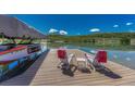 Lakeside dock with boat lift, lounge chairs, and scenic water views surrounded by green hills under a blue sky at 6234 Nautique Cir, Larkspur, CO 80118