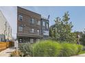 Modern townhouse with brick and metal siding, a small balcony, and lush green landscaping at 1284 Stuart St, Denver, CO 80204