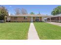 Charming single-story brick home with a well-manicured lawn and inviting walkway at 4728 Dover St, Wheat Ridge, CO 80033