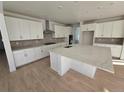 Bright kitchen with white cabinets, a large center island with a stone countertop, and wood floors at 5685 Farrier Pt, Castle Rock, CO 80104