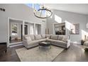 Bright living room with high ceilings, modern chandelier, large sectional sofa, and seamless flow to other rooms at 7863 Windfont Row, Parker, CO 80134