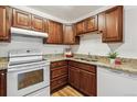Well-lit kitchen features wood cabinetry, stone counters, and modern white oven and dishwasher at 610 S Alton Way # 8D, Denver, CO 80247
