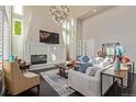 Bright living room features tall ceilings, large windows, fireplace, and modern chandelier at 618 Fairchild Dr, Highlands Ranch, CO 80126