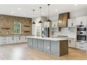 The kitchen features modern appliances, quartz countertops, a large island, and a brick accent wall at 7778 Windwood Way, Parker, CO 80134