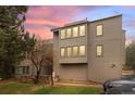 Three-story townhome showcasing large windows and exterior architectural details against a vibrant sunset backdrop at 23551 Genesee Village Rd # H, Golden, CO 80401