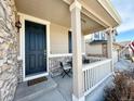 Cozy front porch with a seating area, stone accents, and a welcoming entrance to the home at 25206 E Lake Dr, Aurora, CO 80016