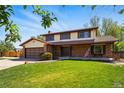 Two-story home features brick accents, a well-kept lawn, and mature trees enhancing its inviting charm at 1354 S Macon St, Aurora, CO 80012