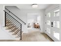 Bright and modern foyer with light wood floors, a staircase with black railings, and a view into the living room at 3930 S Hillcrest Dr, Denver, CO 80237