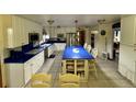 Bright open kitchen with blue countertops, white cabinets, a center island with bar seating, and stainless appliances at 22400 County Road 10, Hudson, CO 80642