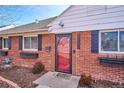 Inviting brick home entrance featuring a red door, updated windows with flower boxes and a 'hello' welcome mat at 1680 Syracuse St, Denver, CO 80220