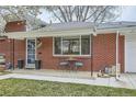 Close up of the charming brick home featuring a cozy front porch seating area at 6970 Upham St, Arvada, CO 80003