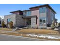 Contemporary home with stone accents, large windows, and a manicured lawn at 6603 Canyonpoint Rd, Castle Pines, CO 80108