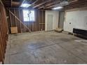 Unfinished two car garage with concrete slab, exposed wood stud framing, and a window at 17900 E Asbury Dr, Aurora, CO 80013