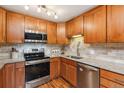 Bright kitchen featuring wood cabinets, stainless steel appliances, tile backsplash, and granite countertops at 9320 E Center Ave # 7A, Denver, CO 80247