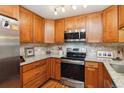 Bright kitchen featuring wood cabinets, stainless steel appliances, tile backsplash, and granite countertops at 9320 E Center Ave # 7A, Denver, CO 80247
