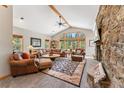 Inviting living room features stone fireplace, vaulted ceilings, large windows, and leather furniture at 387 Moonstone Rd, Breckenridge, CO 80424
