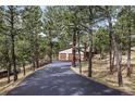 A long black paved driveway leads to a three car garage, surrounded by mature trees at 2857 Hiwan Dr, Evergreen, CO 80439