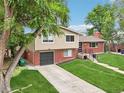 Beautiful two-story home featuring a brick facade, attached garage, and lush green lawn at 6320 E Asbury Ave, Denver, CO 80224