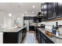 Spacious kitchen featuring dark cabinets, granite countertops, stainless steel appliances, and wood floors at 6784 Navajo St, Denver, CO 80221