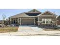 Inviting single-story home featuring a two-car garage, stone accents, and a well-manicured lawn and garden at 12708 Tamarac St, Thornton, CO 80602