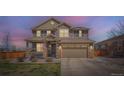 Charming two-story home with a covered front porch illuminated against a colorful twilight sky at 9574 Keystone Trl, Parker, CO 80134
