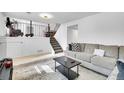 Comfortable living room with soft gray couch, decorative pillows, black coffee table, and a staircase in the background at 5183 Durham Ct, Denver, CO 80239