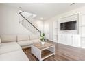 Comfortable living room with a neutral sofa, built-in shelving, and staircase at 22921 E Union Ave, Aurora, CO 80015