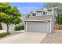 Gray two-story townhome featuring an attached two-car garage and landscaped front yard at 12717 E Cornell Ave, Aurora, CO 80014
