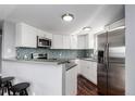 Bright kitchen features stainless steel appliances, blue tile backsplash and a breakfast bar with seating at 5250 S Huron Way # 13-312, Littleton, CO 80120