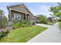 Charming home with a well-manicured lawn, beautiful landscaping, and a cozy front porch, creating a welcoming curb appeal at 8056 Piney River Ave, Littleton, CO 80125