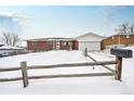 Brick ranch home with attached garage, snowy yard, and wooden fence at 13390 W 8Th Ave, Lakewood, CO 80401