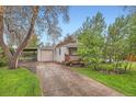 Charming single-story home featuring a detached garage and a cozy front porch with wood trim details at 4285 Newland St, Wheat Ridge, CO 80033