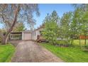 Inviting single-story home with a detached garage and a charming front porch nestled among mature trees at 4285 Newland St, Wheat Ridge, CO 80033